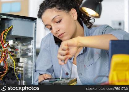 woman on the phone with screwdriver setting up a computer