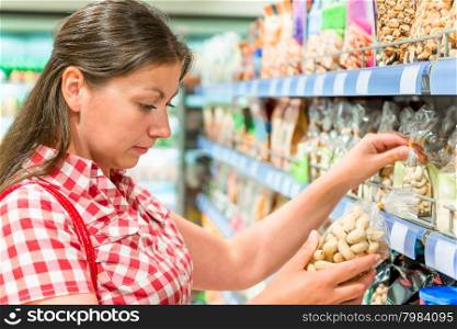 woman on the shelf at the store chooses the nuts