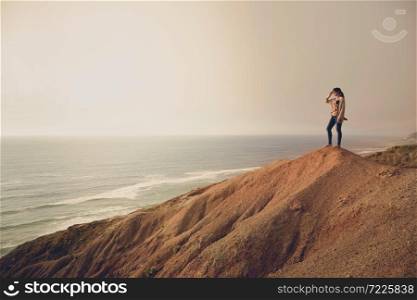 Woman on the top of a clif looking to the ocean
