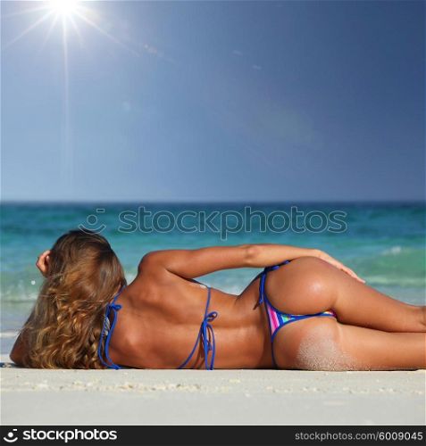 Woman on tropical beach. Rear view of sexy woman in bikni lying on topical beach