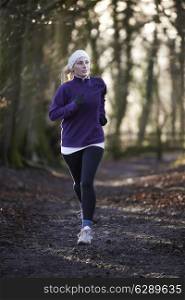 Woman On Winter Run Through Woodland