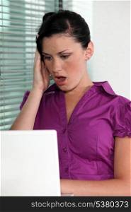 Woman open mouthed in shock at her computer