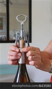 Woman opening a bottle of wine with a corkscrew