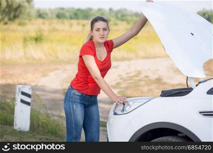 Woman opening hood of the broken car at roadside