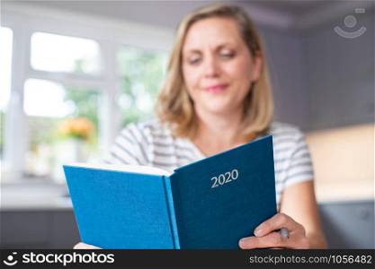 Woman Opening New Year 2020 Diary On Table At Home