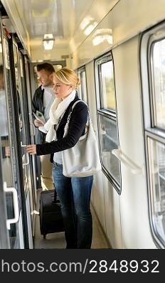 Woman opening the door of train compartment carrying luggage travel