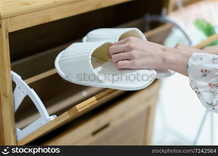 Woman opening wooden shoes storage cabinet for keep her shoes.