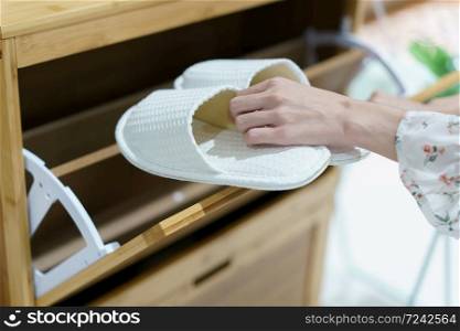 Woman opening wooden shoes storage cabinet for keep her shoes.