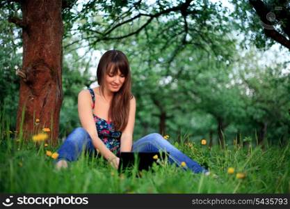 Woman outdoor sitiing with netbook and smiling