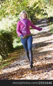 Woman outdoors at park running on path smiling (selective focus)