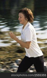 Woman outdoors by a stream running and smiling (selective focus)