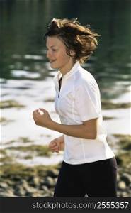 Woman outdoors by a stream running and smiling (selective focus)