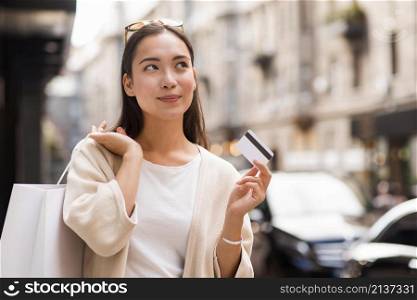 woman outdoors holding credit card shopping bag