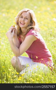 Woman outdoors holding flower smiling