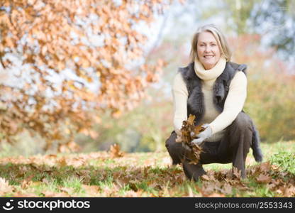 Woman outdoors holding leaves and smiling (selective focus)