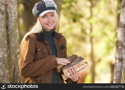 Woman Outdoors In Autumn Woodland Gathering Logs