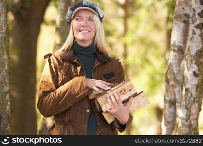 Woman Outdoors In Autumn Woodland Gathering Logs