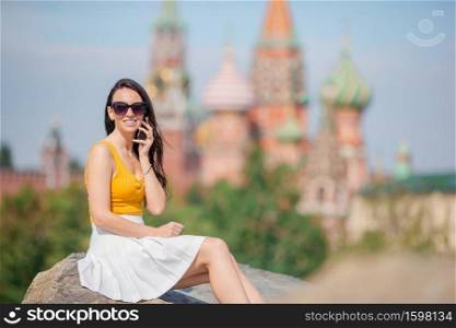 Woman outdoors in big city talking by smartphone. Happy young urban woman in european city.