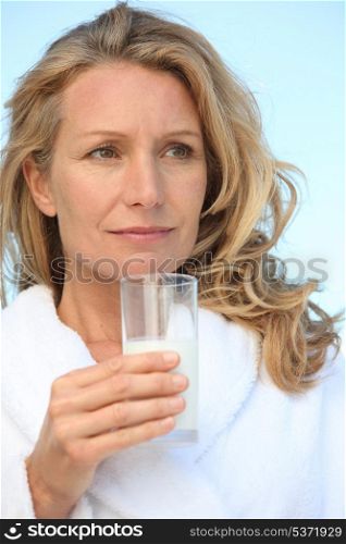 Woman outdoors in dressing gown holding glass of milk