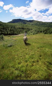 Woman outdoors riding horse in scenic location