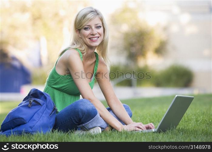 Woman outdoors sitting on grass with laptop (selective focus)