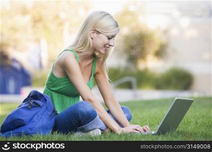 Woman outdoors sitting on grass with laptop (selective focus)