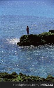 Woman outdoors standing on large rocks Oceanside (far away)
