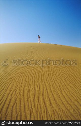 Woman outdoors walking in the desert (far away)