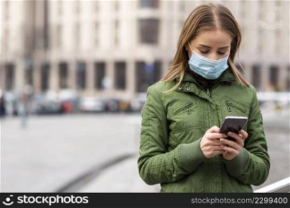 woman outdoors wearing mask using mobile phone