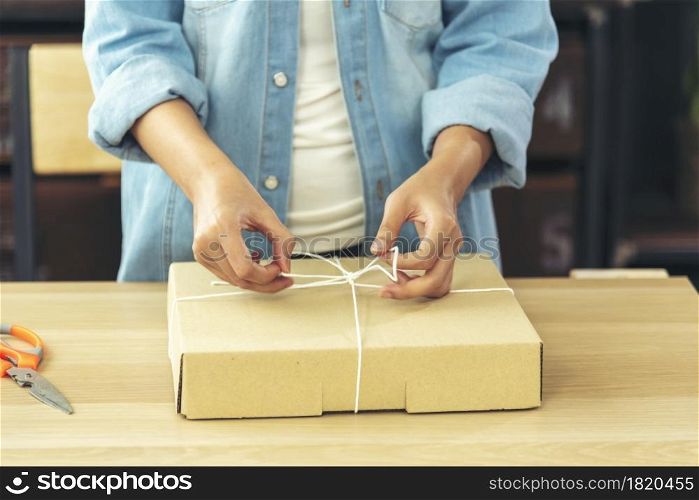 Woman packing box on table checking goods package delivery shipping to customer. Asian woman startup small business at home office desk. Entrepreneur asian woman packing product for delivery items