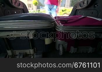 Woman packing her luggage into car trunk inside view