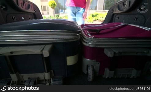 Woman packing her luggage into car trunk inside view