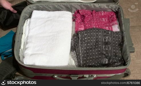 Woman packing suitcase on bed for summer vacation time-lapse