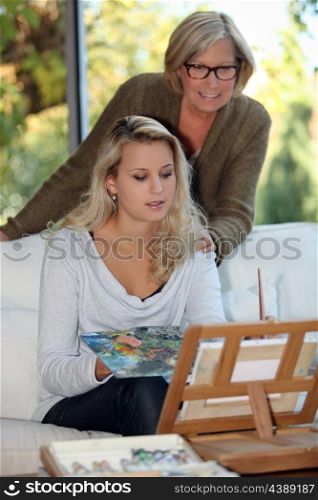 Woman painting as mother watches