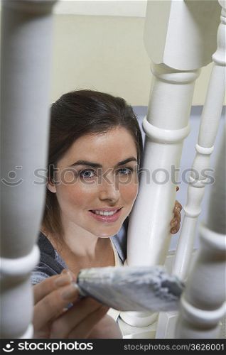 Woman painting behind banister