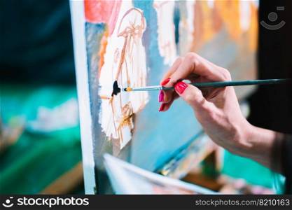 Woman paints a painting on canvas. Art academy or drawing school. Girl paints on the easel. Only hand of unknown artist, brush and canvas. Woman paints a painting on canvas. Art academy or drawing school. Girl paints on the easel. Only hand of unknown artist, brush and canvas.