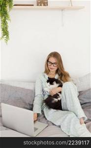 woman pajamas working from home laptop while holding cat