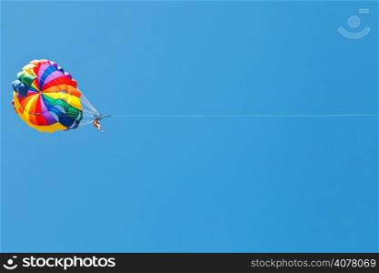 woman parakiting on parachute in blue sky in summer day