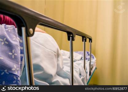 Woman patient lying on a bed in a hospital room.