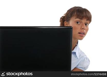 Woman peeking out from behind a laptop