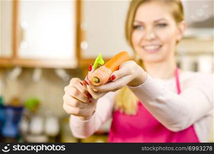 Woman peeling vegetables using food peeler. Cooking female preparing carrot before serving.. Woman peeling carrot vegetable
