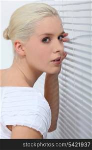 Woman peering through some blinds