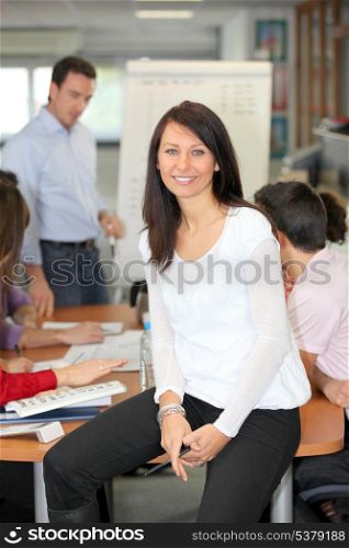 Woman perched on desk during business meeting