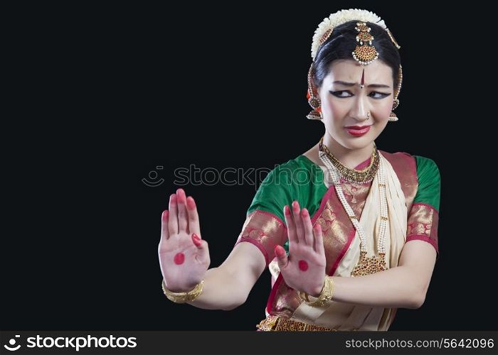 Woman performing Bharatanatyam over black background