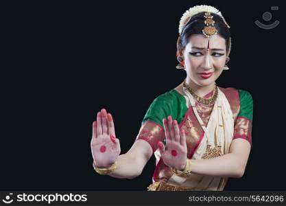 Woman performing Bharatanatyam over black background