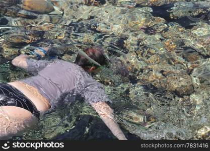 Woman photographer diving into water of Red sea