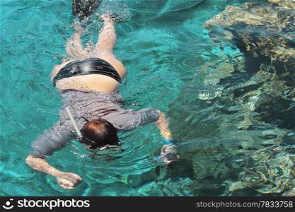 Woman photographer diving into water of Red sea