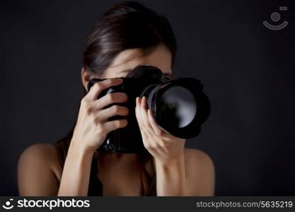 Woman photographer taking photograph against black background