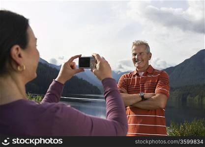 Woman photographing man, mountains in background