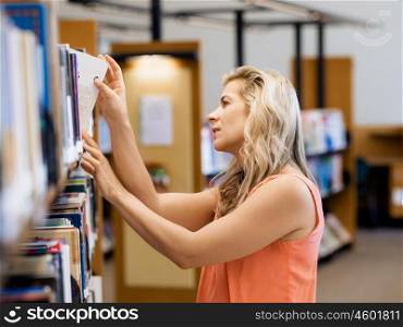 Woman picking a book in public library. That is a difficult choice